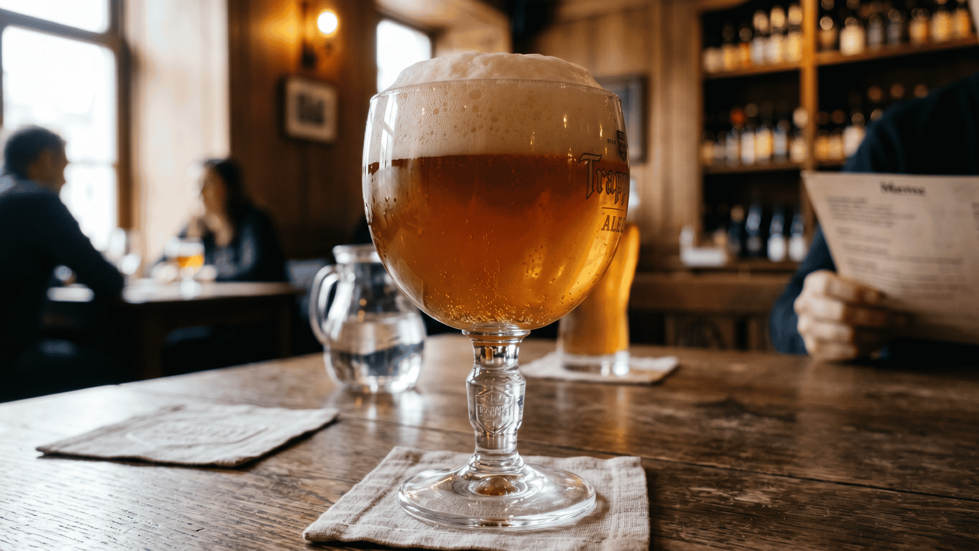 Dark beer in elegant goblet glass on rustic wooden table in pub interior