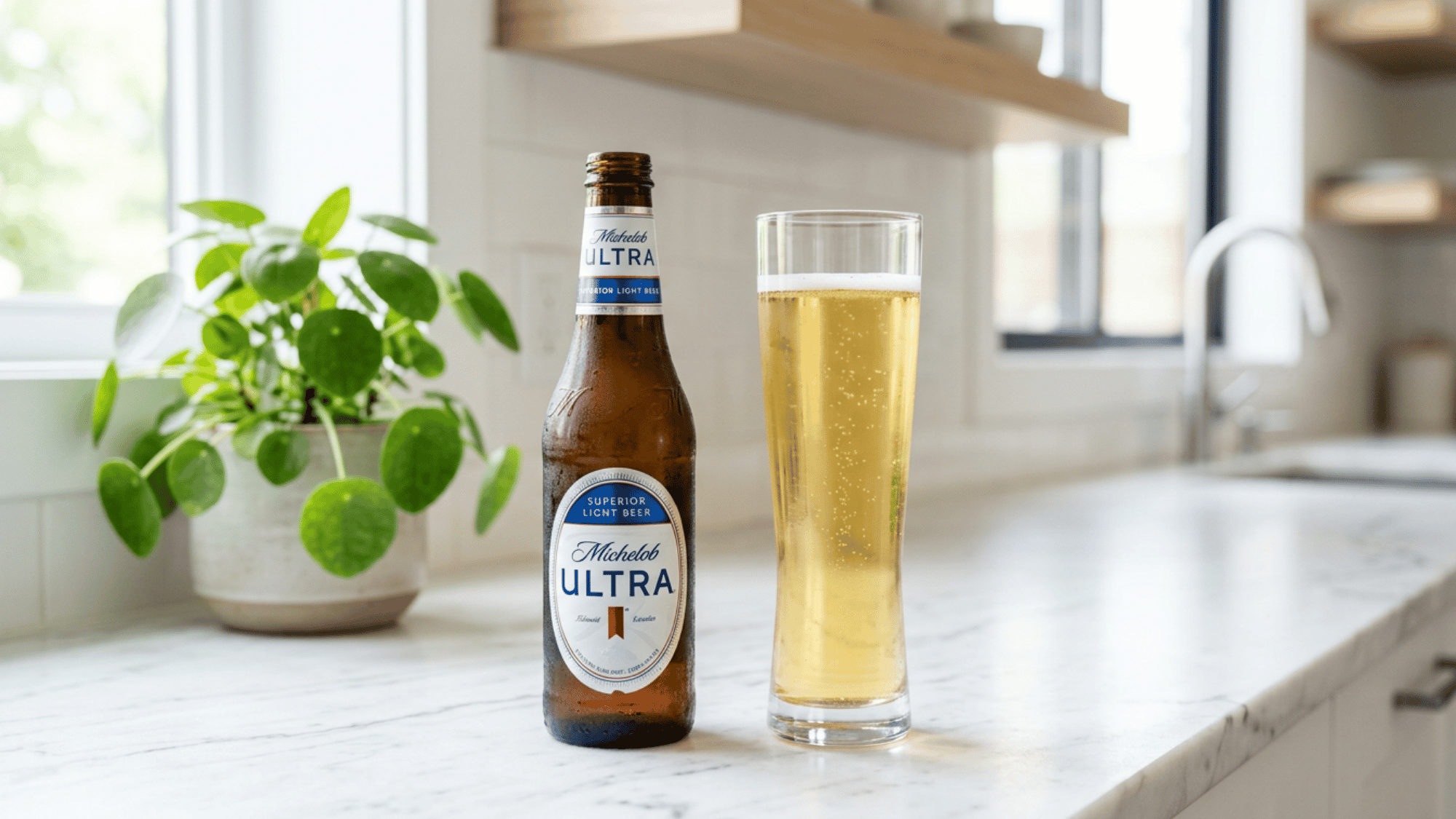 Michelob Ultra bottle and tall glass on white marble kitchen counter