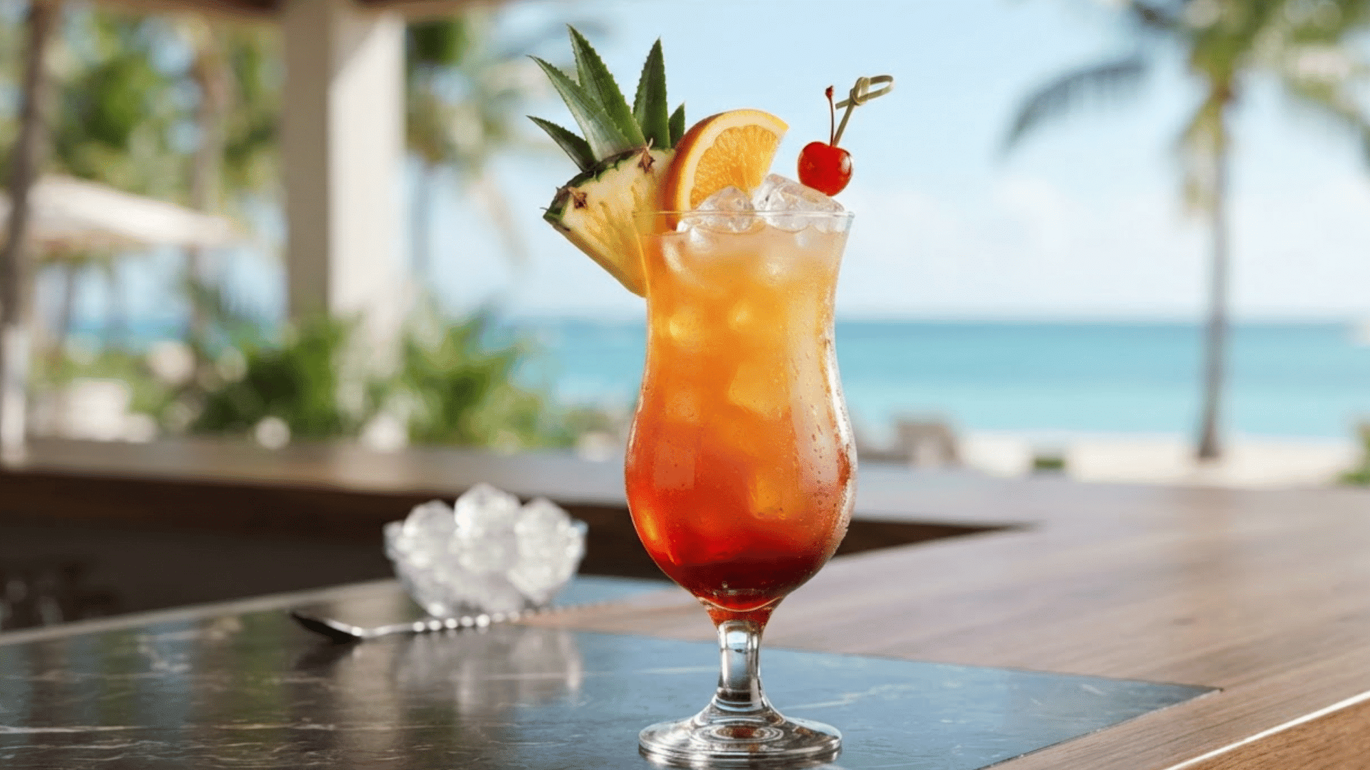 Bahama Mama cocktail with tropical fruit color, ice, pineapple, and cherry.