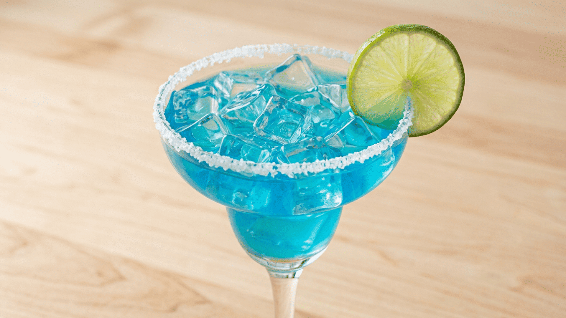 Bright blue curaçao margarita with a salt rim and lime wheel