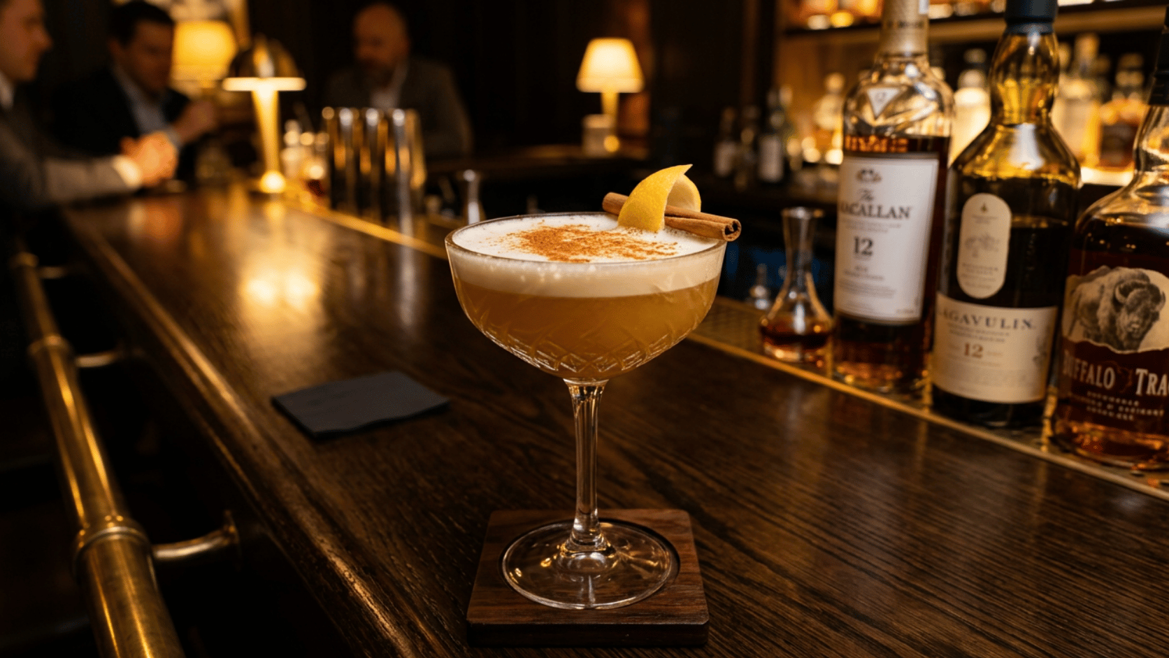 Frothy Cinnamon Whiskey Sour in a coupe glass, dusted with cinnamon and garnished with lemon peel.