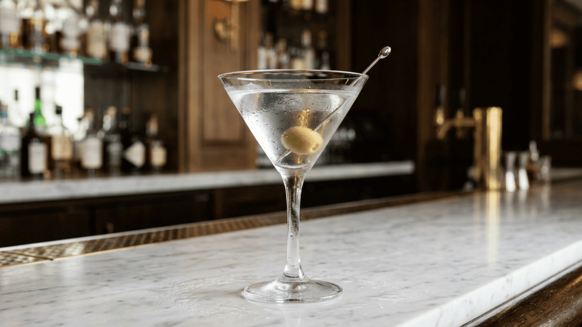 Chilled martini with olive garnish on a marble bar counter