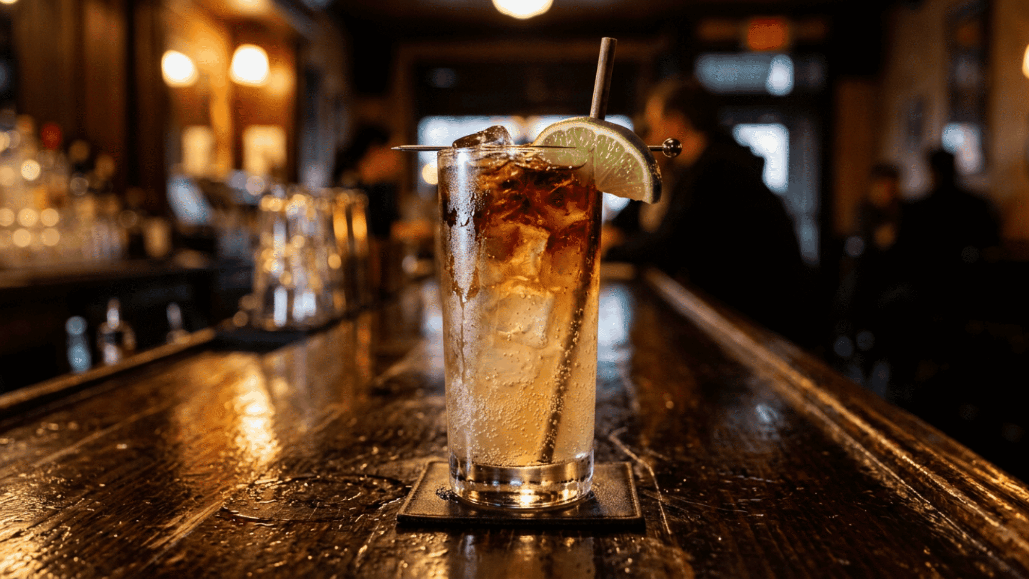Dark and Stormy cocktail with lime on a warm wooden bar