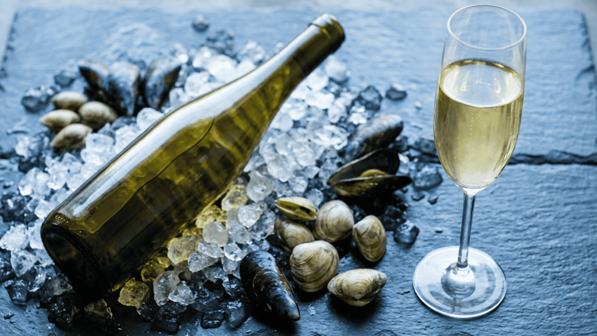 Chilled Dry Riesling bottle on ice with shellfish and a sparkling glass of white wine.