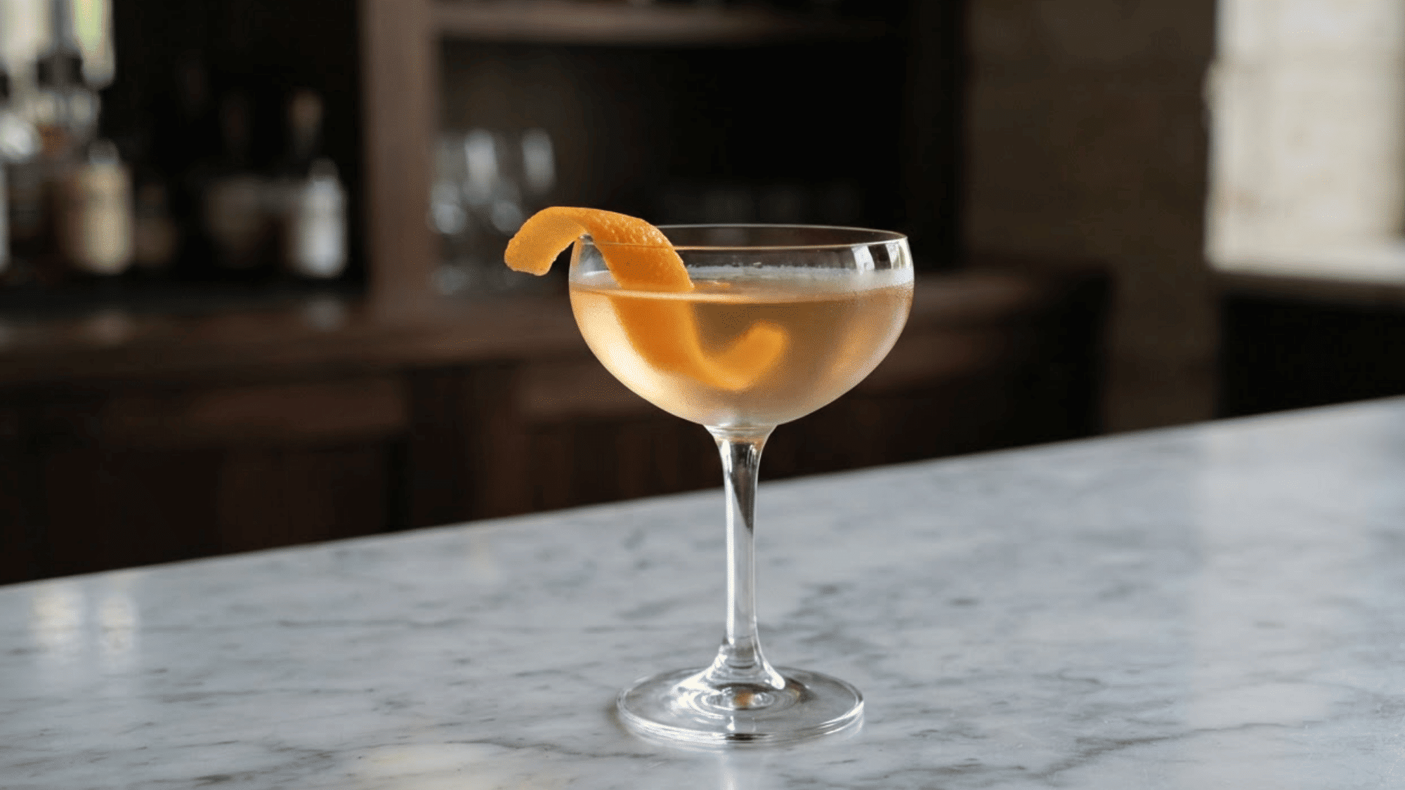 El Presidente cocktail in a coupe glass with golden color and orange twist.