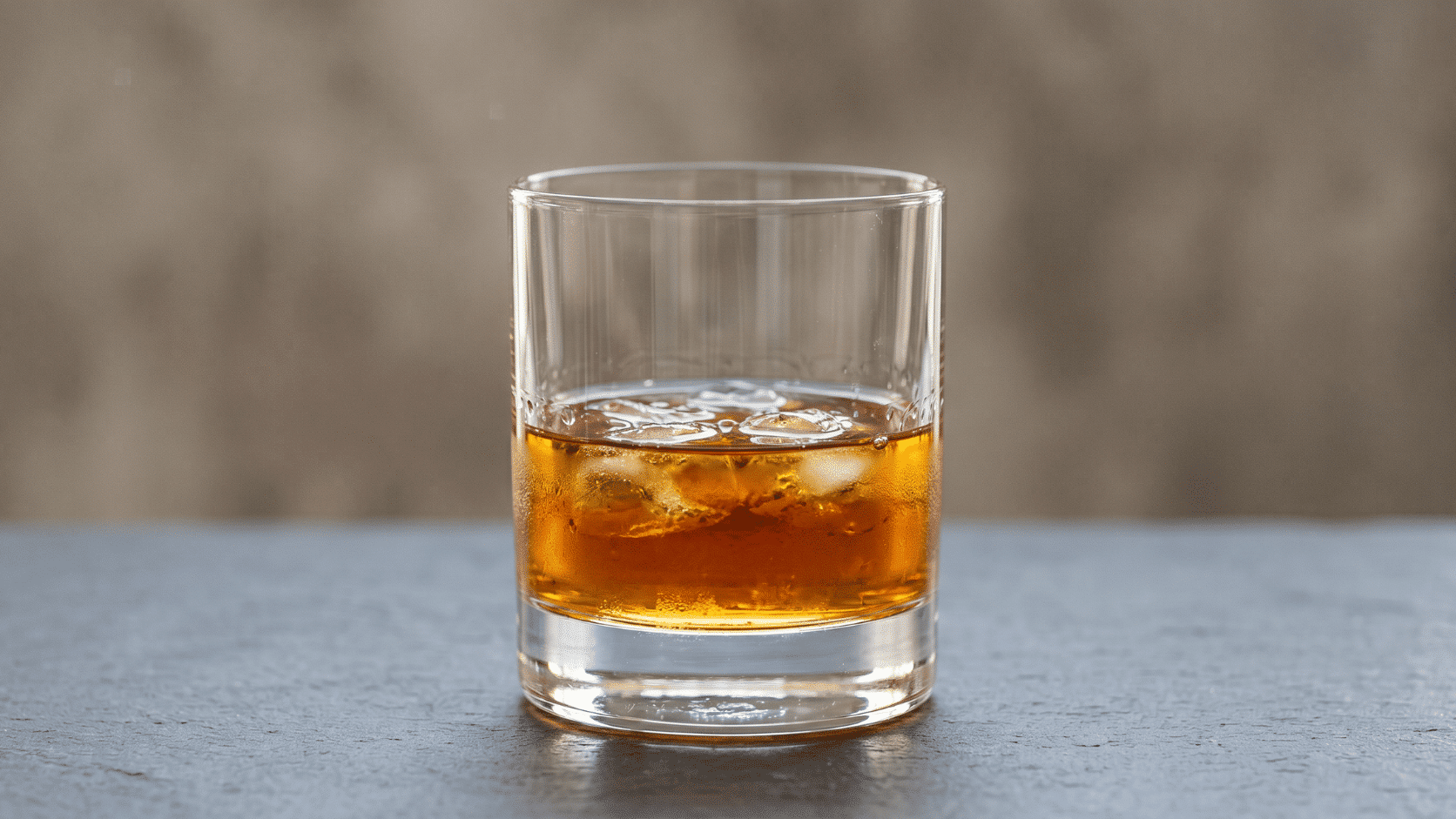 Flavored whiskey glass with amber liquid, soft studio lighting, neutral background.