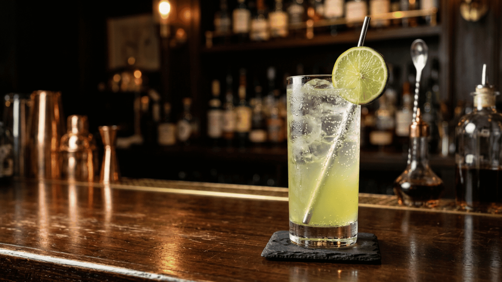 Gin rickey cocktail with lime and ice in a moody bar setting