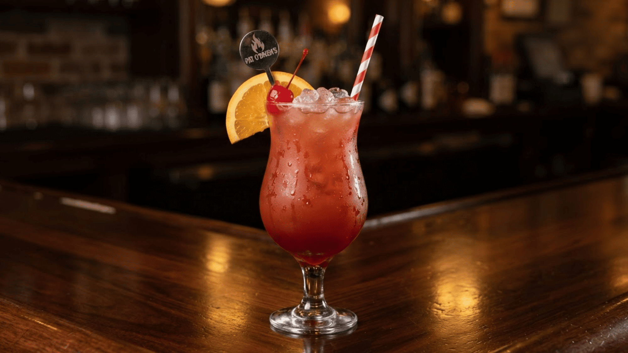 Hurricane cocktail with red-orange fruit drink, ice, orange, and cherry garnish.