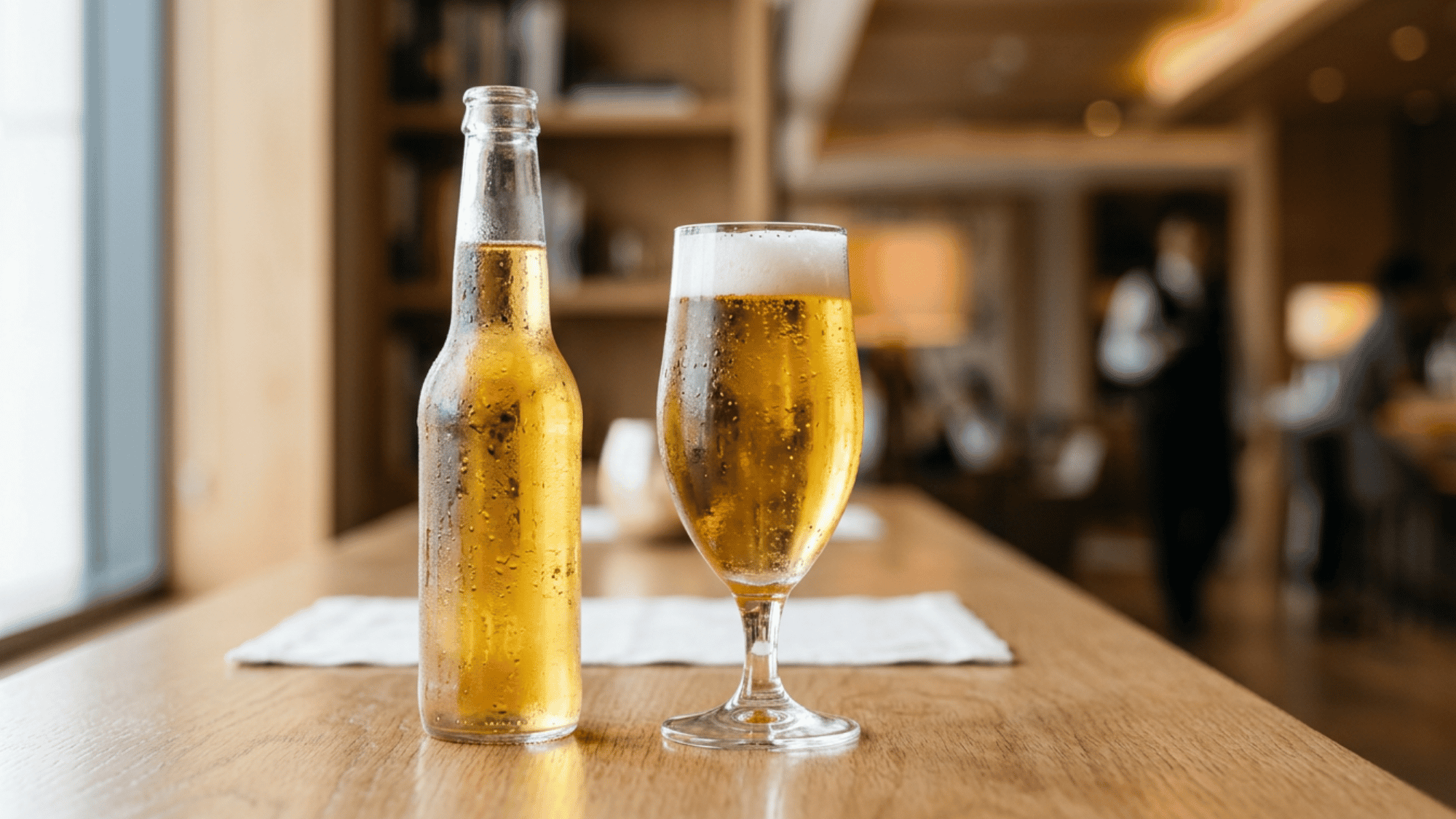 Light beer bottle and glass on a table top.