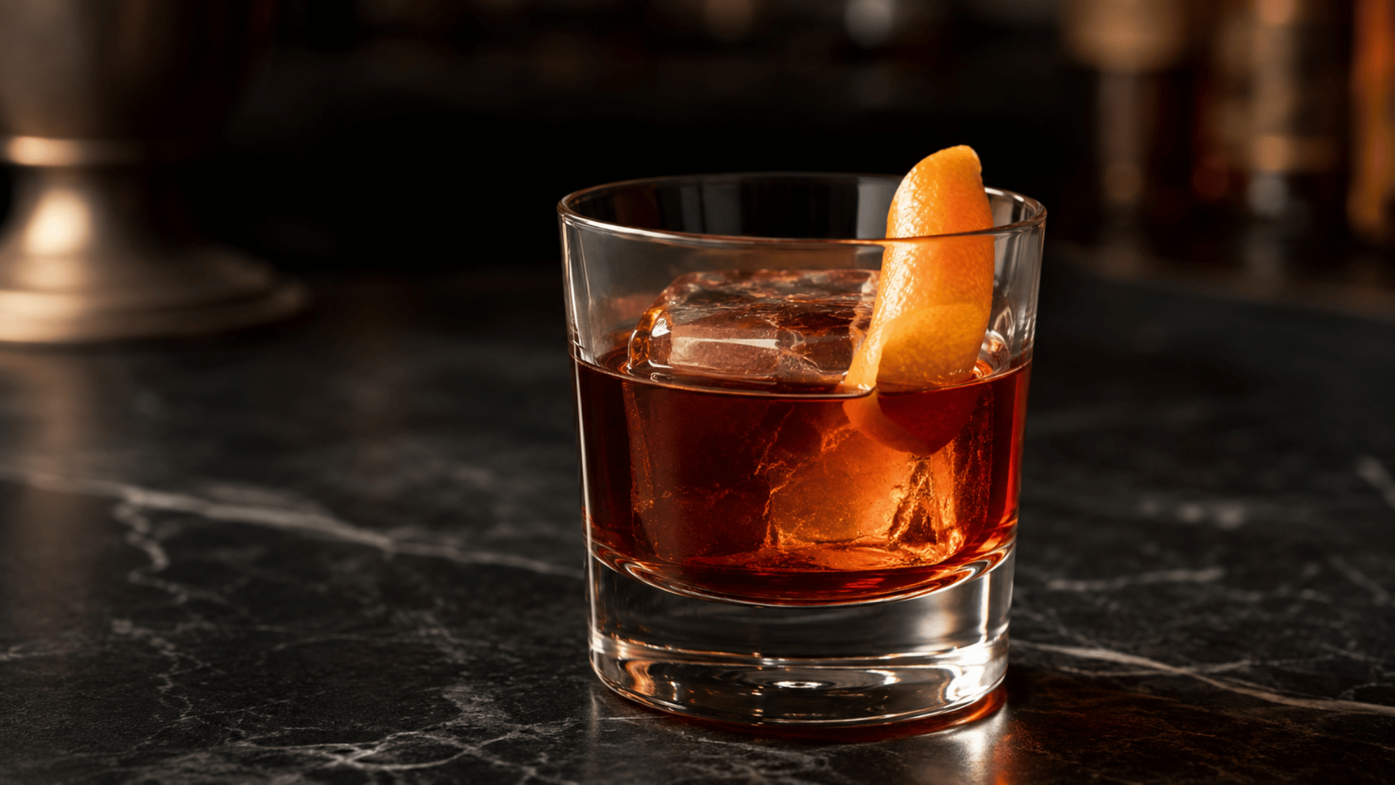 Boulevardier cocktail with orange peel and ice on a dark stone bar