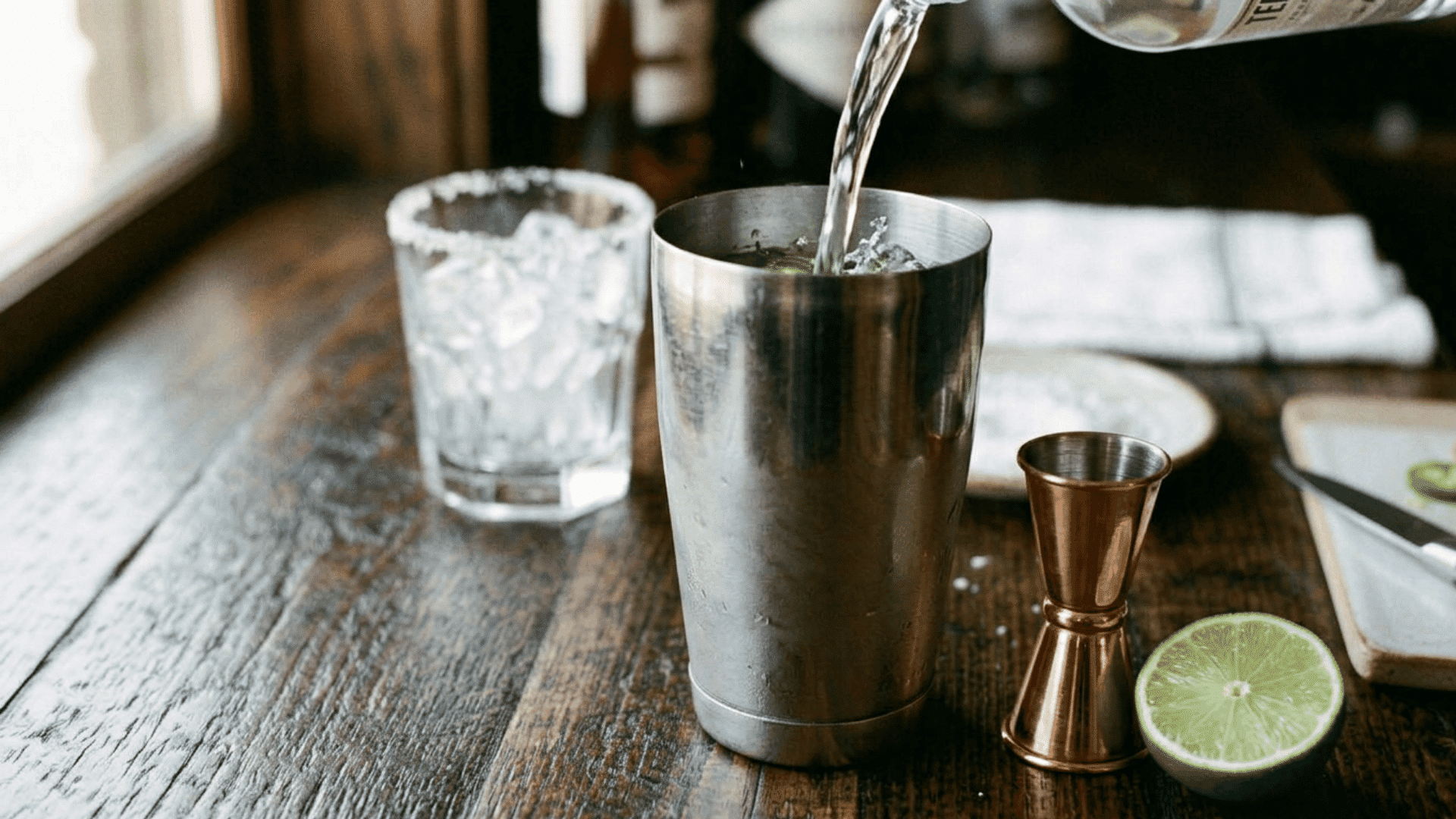 Tequila poured into a shaker with muddled jalapeño and lime