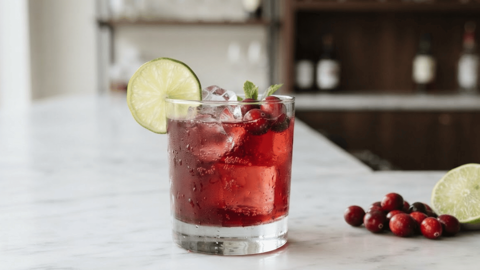 Rum Cranberry cocktail with deep red color, ice, and lime wheel garnish.