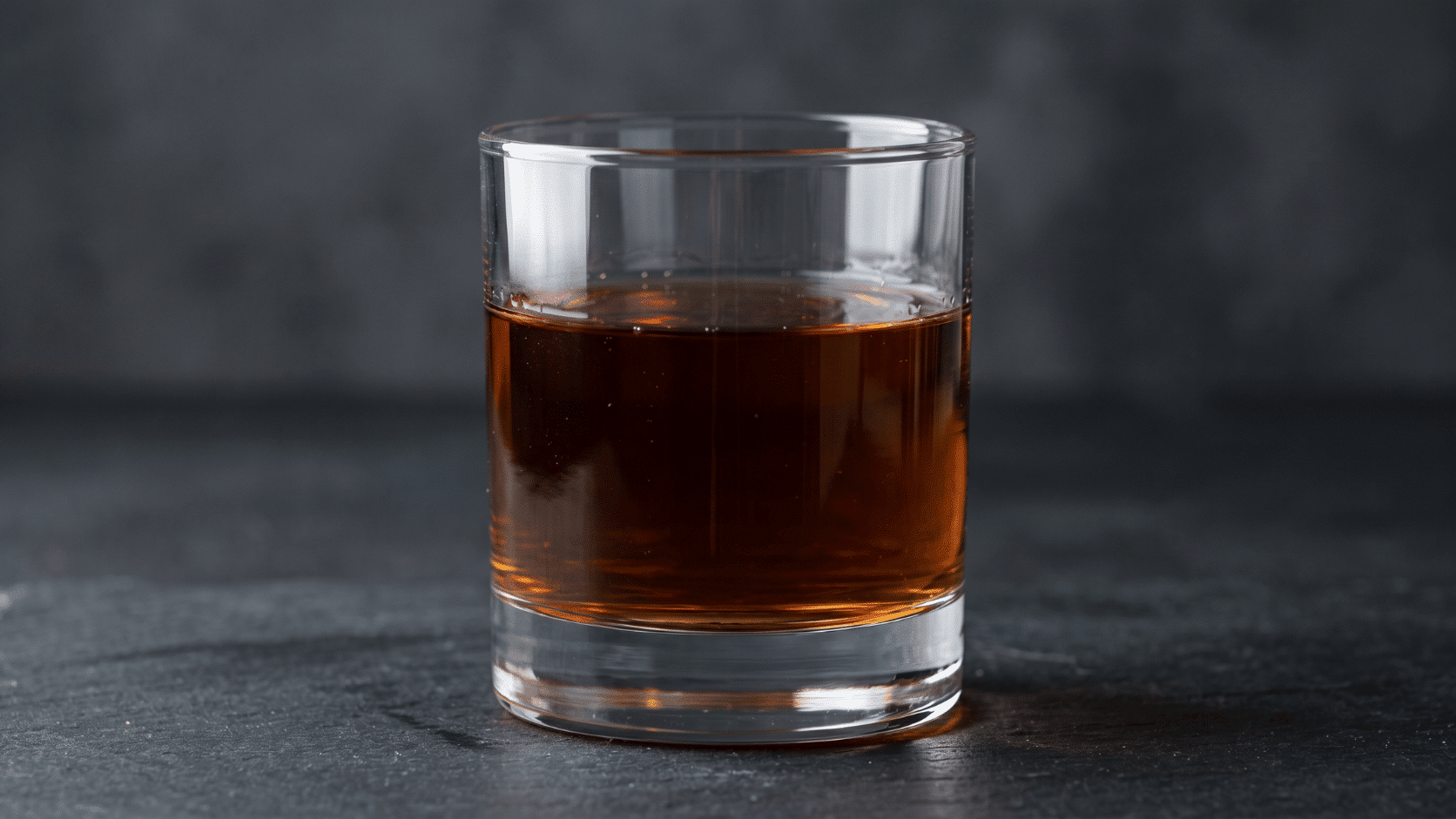 Close-up of rye whiskey in a glass with deep amber liquid on dark textured studio background photo.