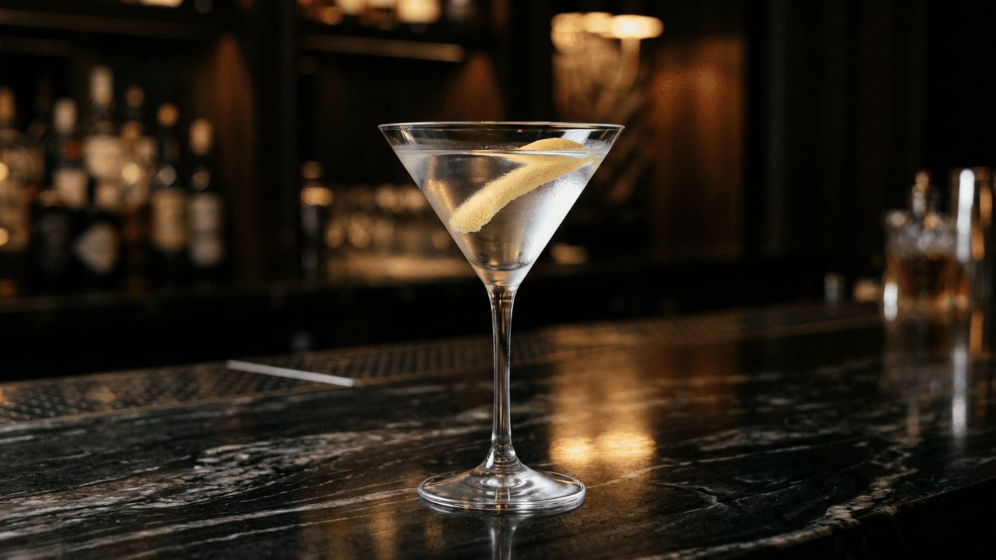 Vesper martini with a lemon peel garnish on a dark bar counter