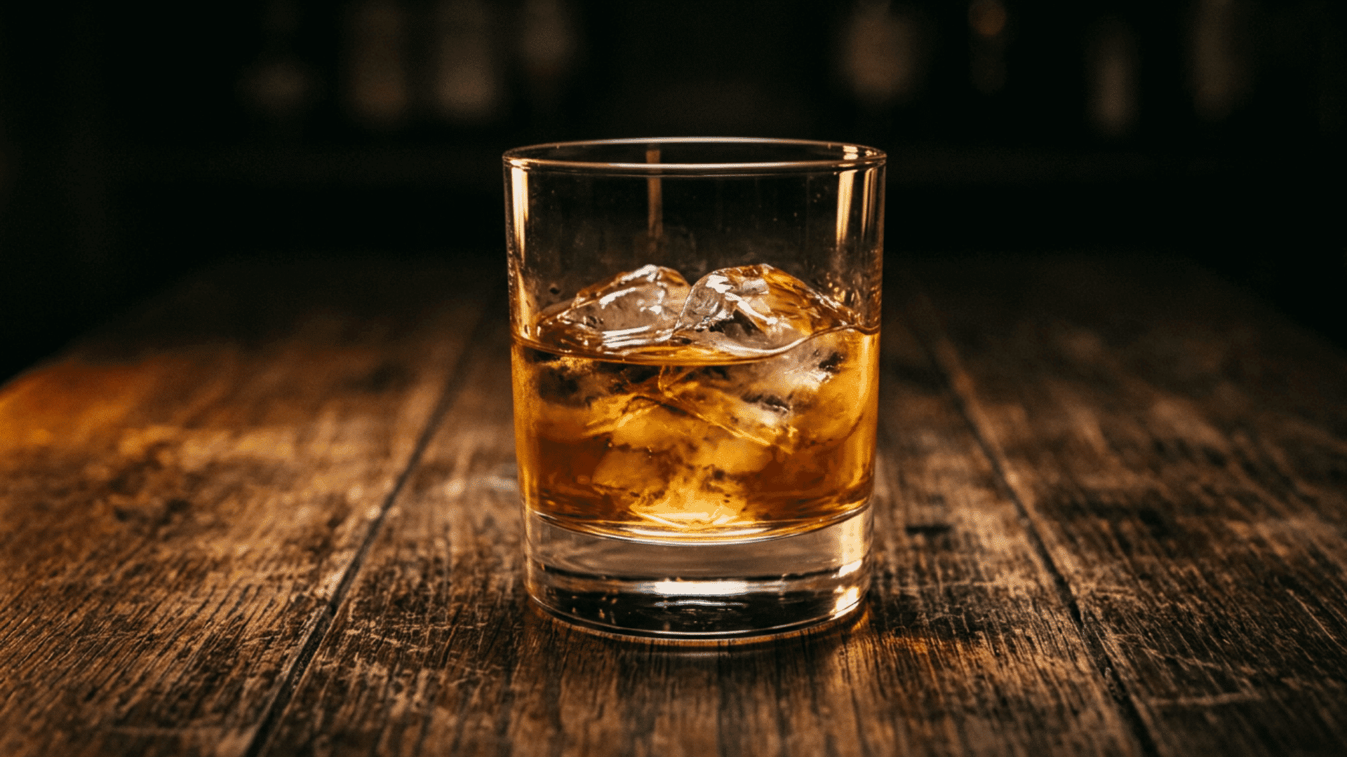 Amber whiskey glass resting on oak barrel in cellar.