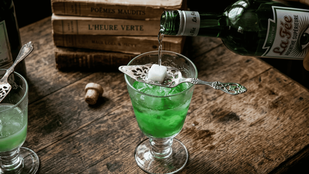 Absinthe poured over a sugar cube into a green-filled glass during traditional preparation.