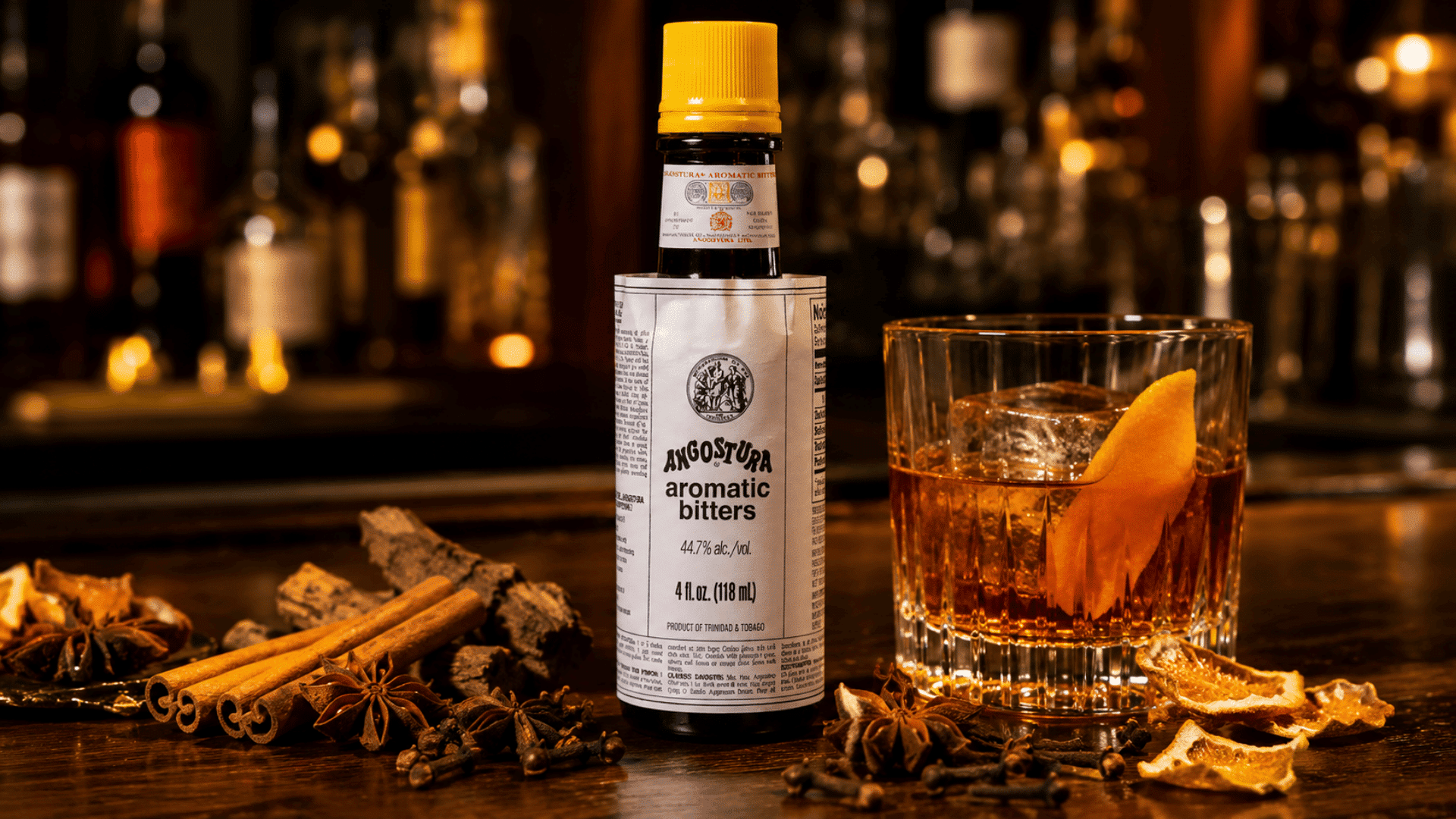 aromatic bitters with cinnamon, cloves, bark spices, and an old fashioned cocktail on a warm wooden bar surface