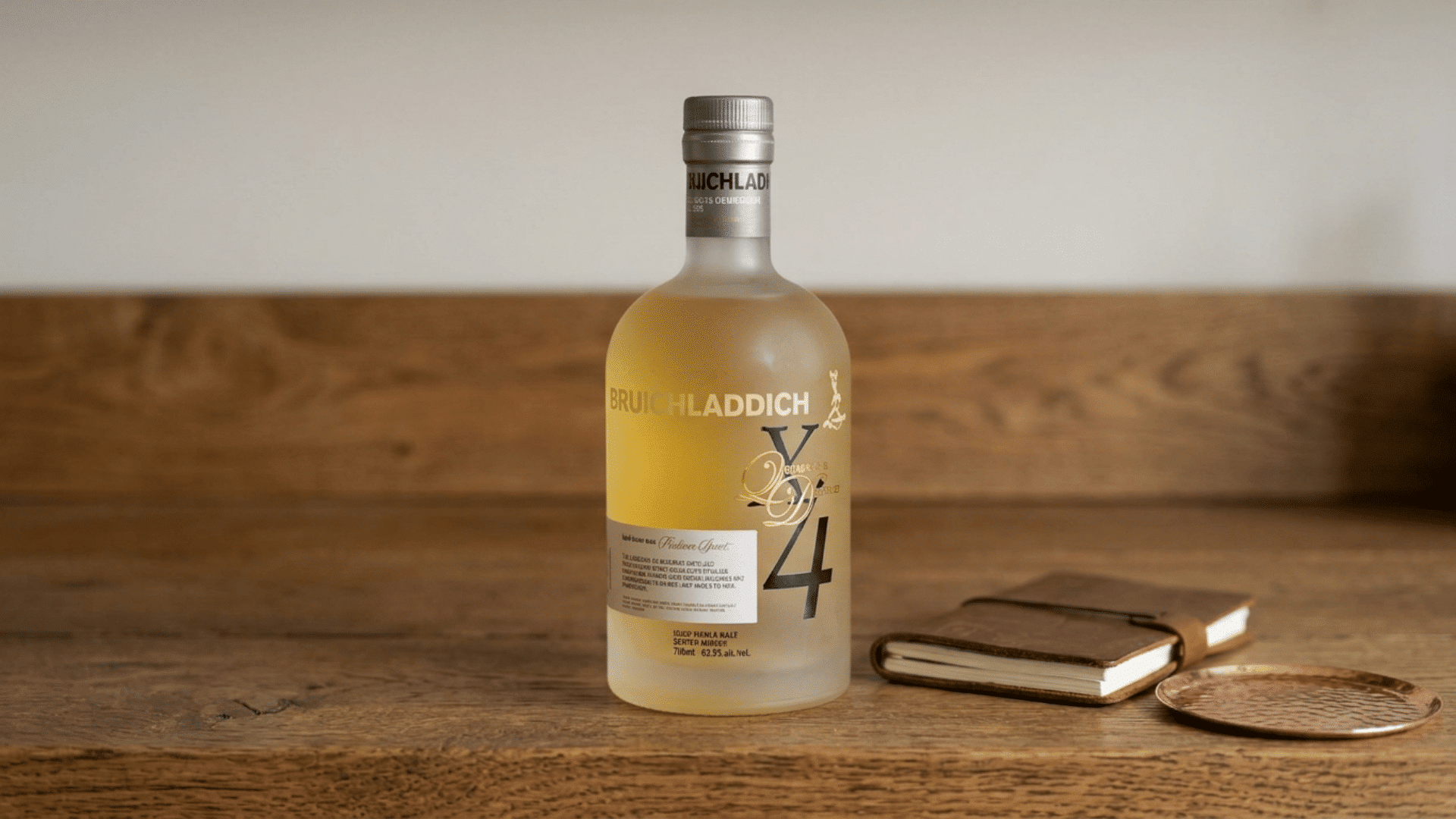 bruichladdich x4 whisky bottle with notebook and copper coaster on wood table