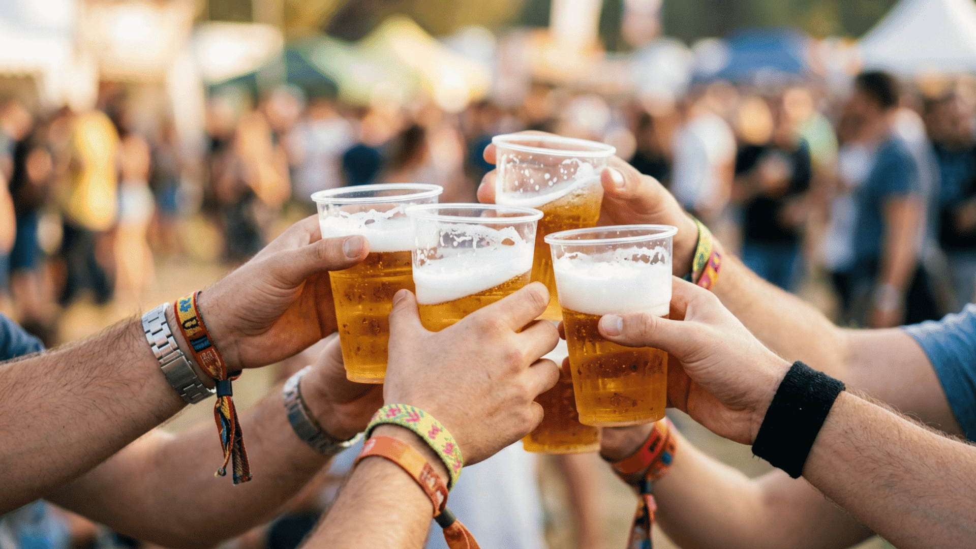 Group of friends toasting with beer cups at an outdoor festival