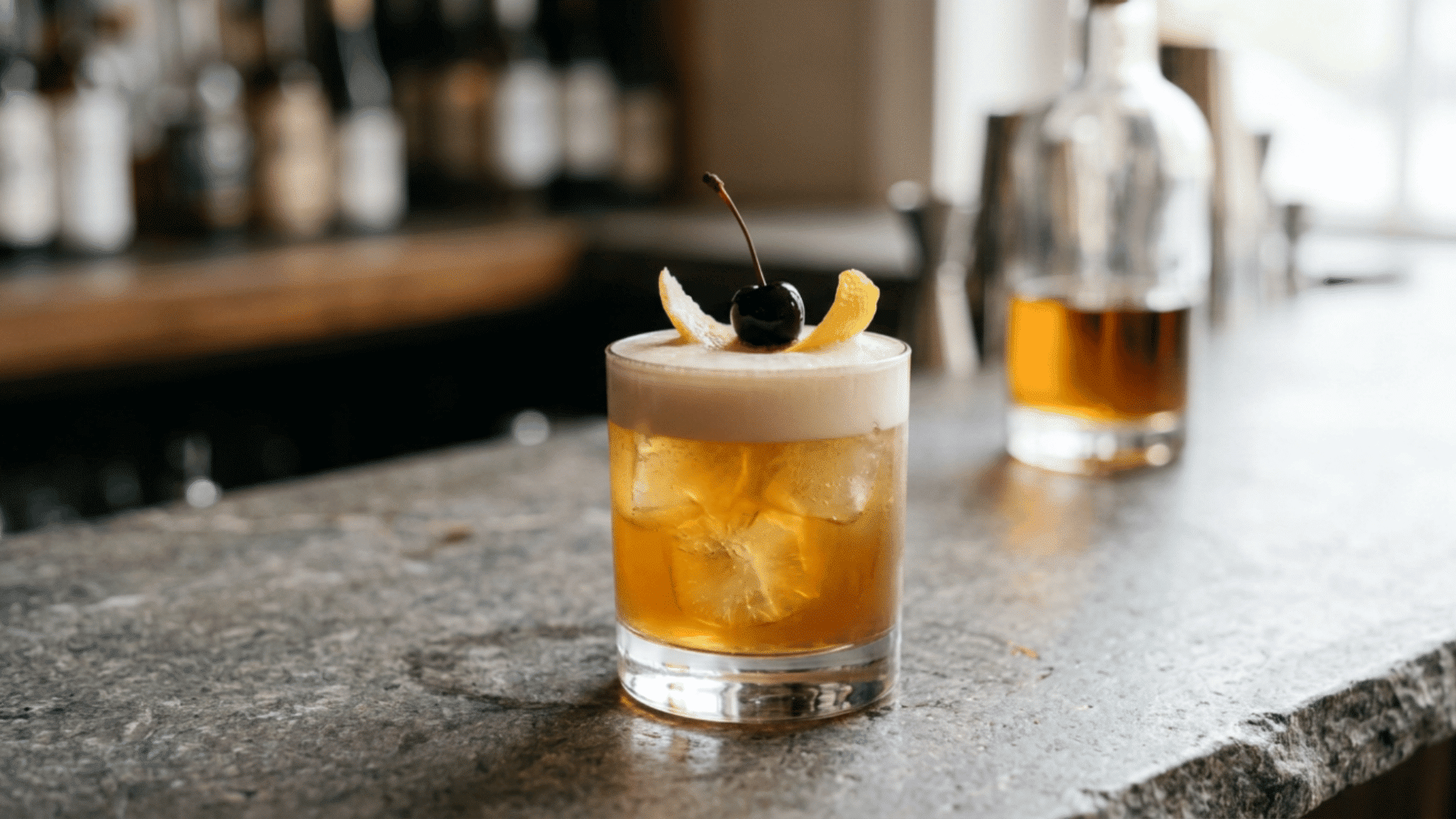 garnishes a finished whiskey sour with lemon peel and cherry