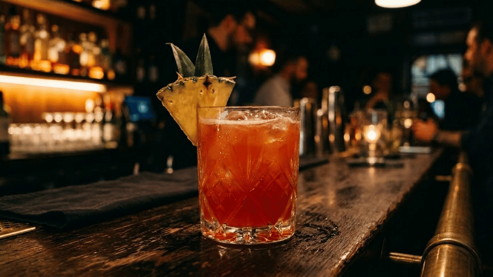 jungle Bird cocktail in crystal glass with pineapple garnish in dark moody bar setting