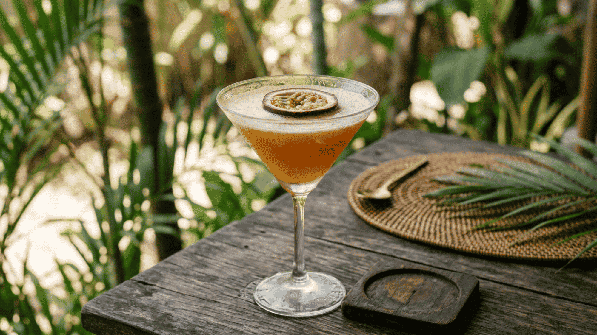 Passion Fruit Martini with dried passion fruit garnish served in a martini glass on a rustic tropical table.