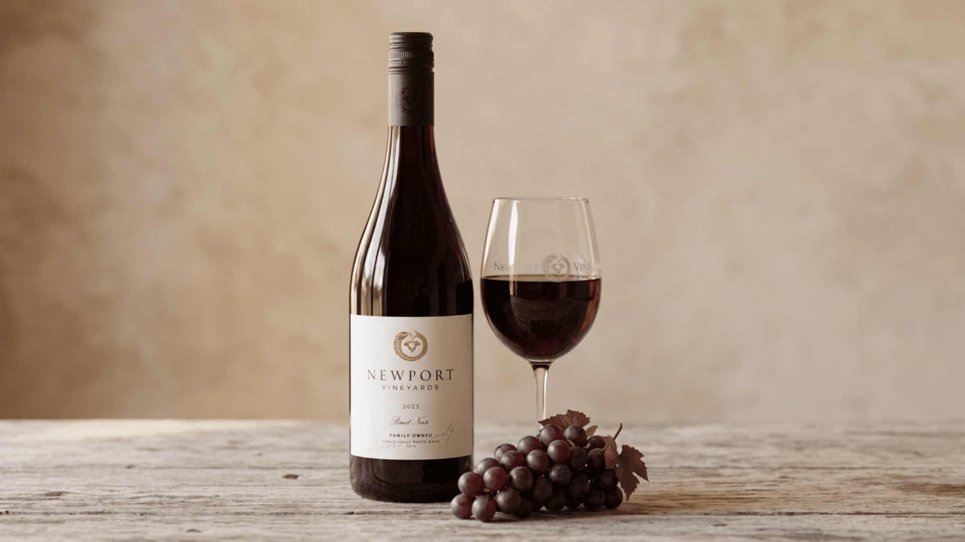 Pinot Noir bottle and glass with grapes showing a dry wine tasting scene.