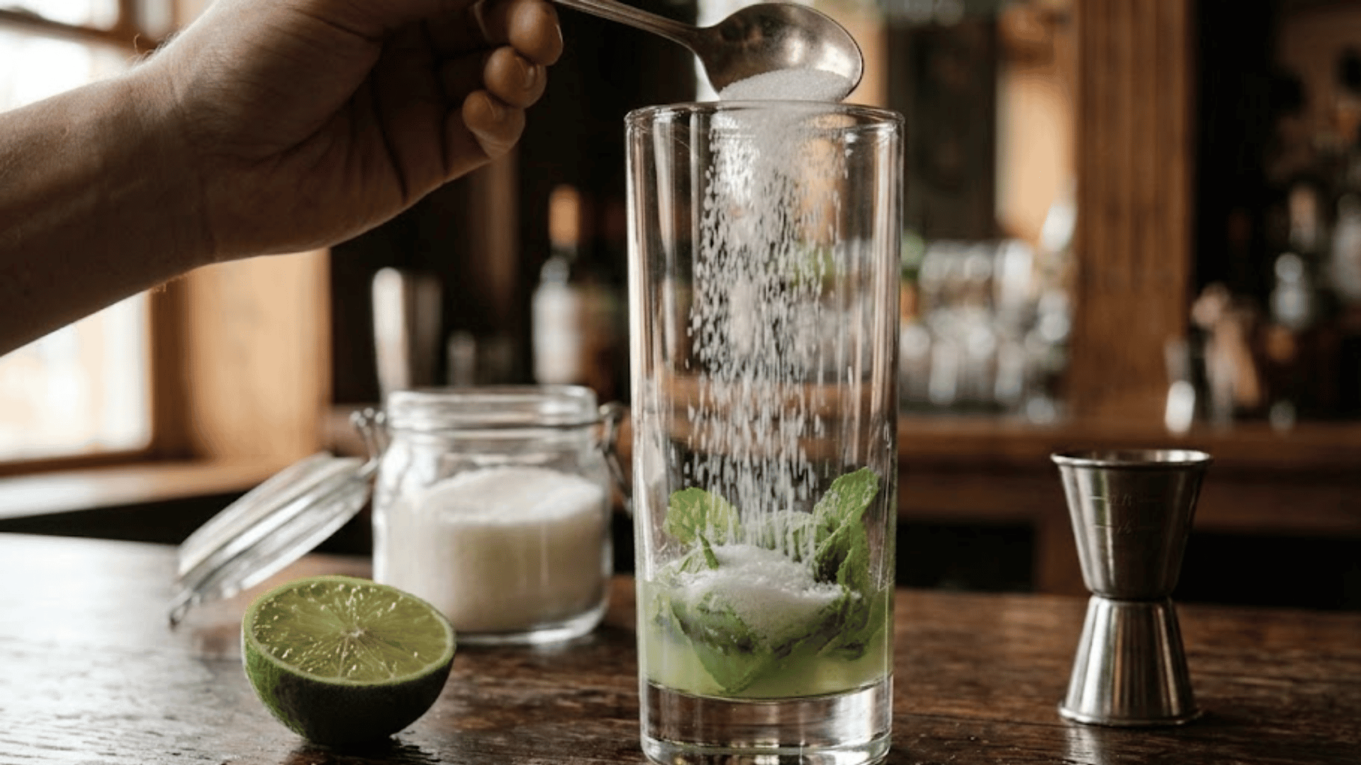 sugar added to mint and lime juice in a tall glass