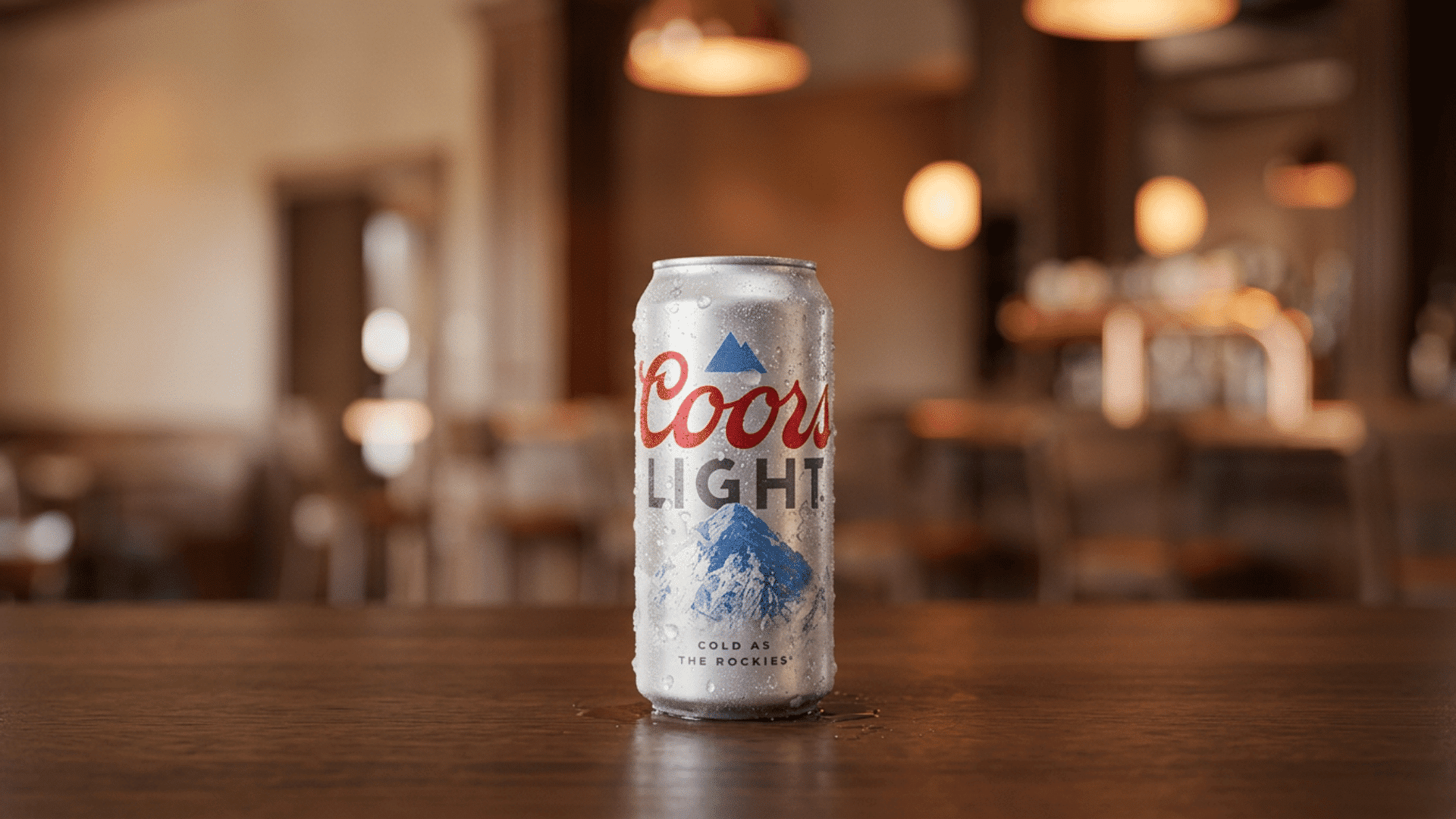cold coors light beer can on a wooden counter in a warmly lit restaurant