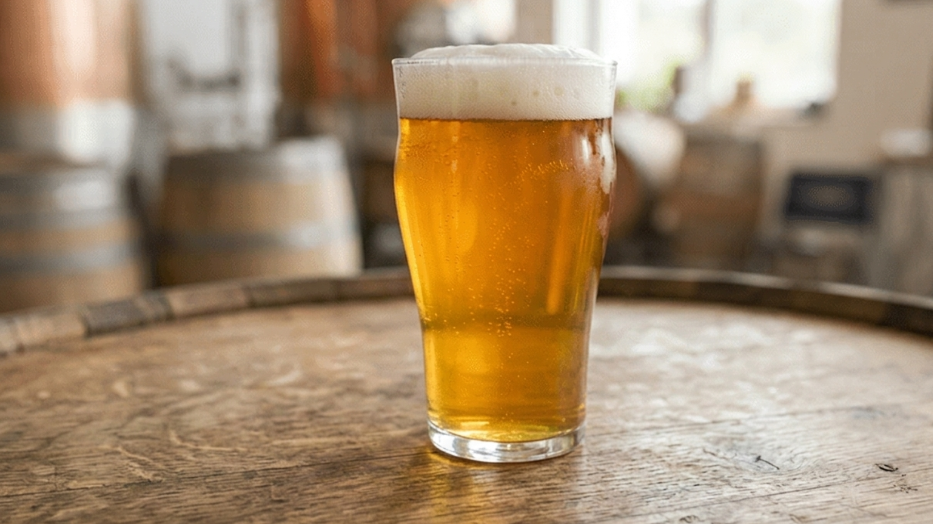 golden India pale ale surrounded by several hop cones on a wooden surface