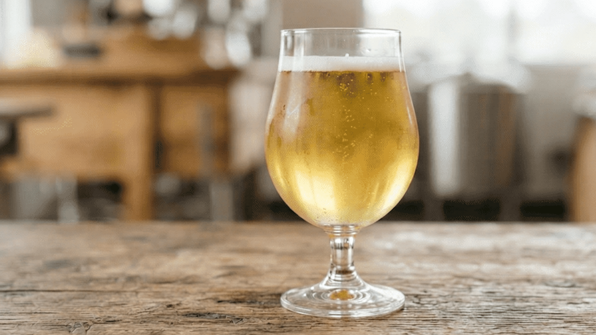 pale golden light lager beside a few hop cones on a wooden surface