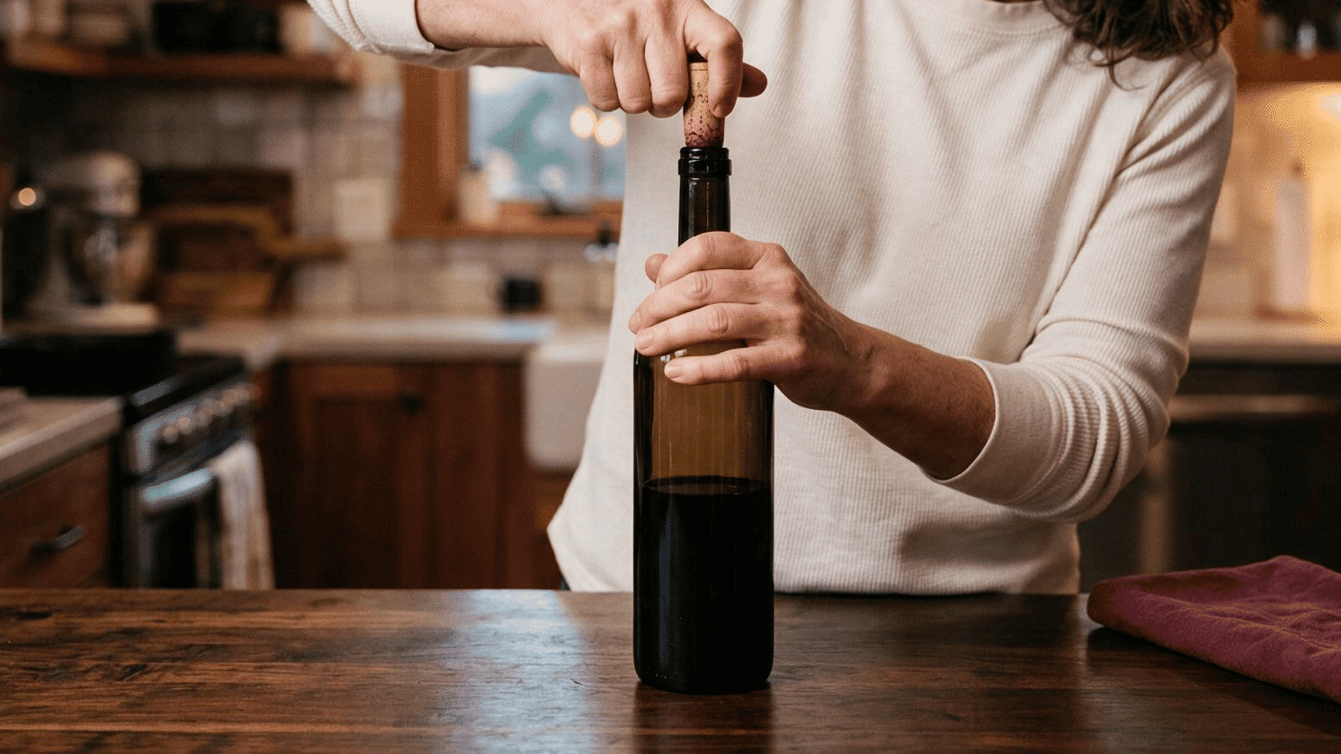 woman sealing an opened red wine bottle tightly with a cork
