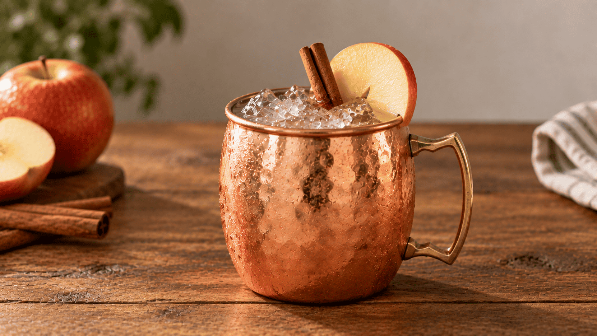Spiced apple mule in a copper mug with ice, thin apple slice and cinnamon stick garnish
