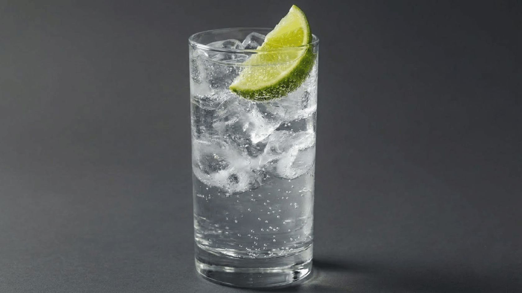 tequila soda drink with a black background and a lime garnish over ice